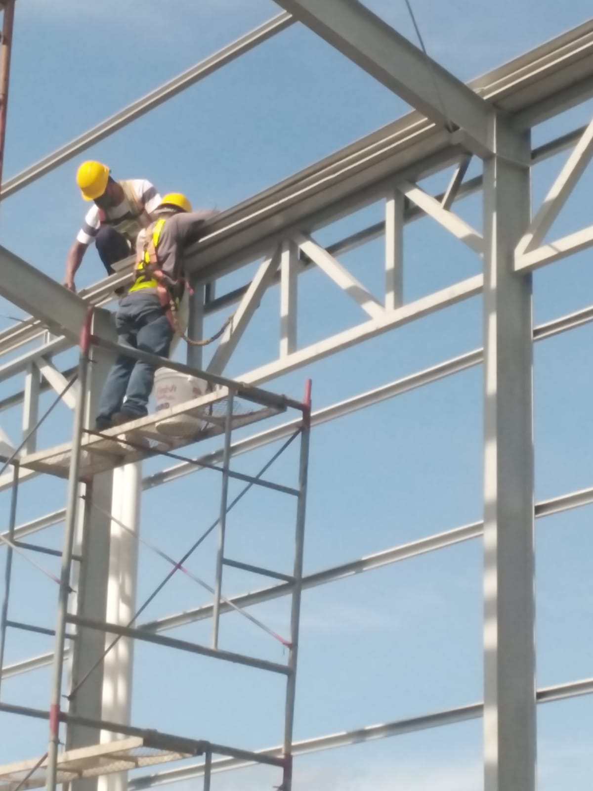 Montaje de estructura metálica industrial con grúa y personal especializado